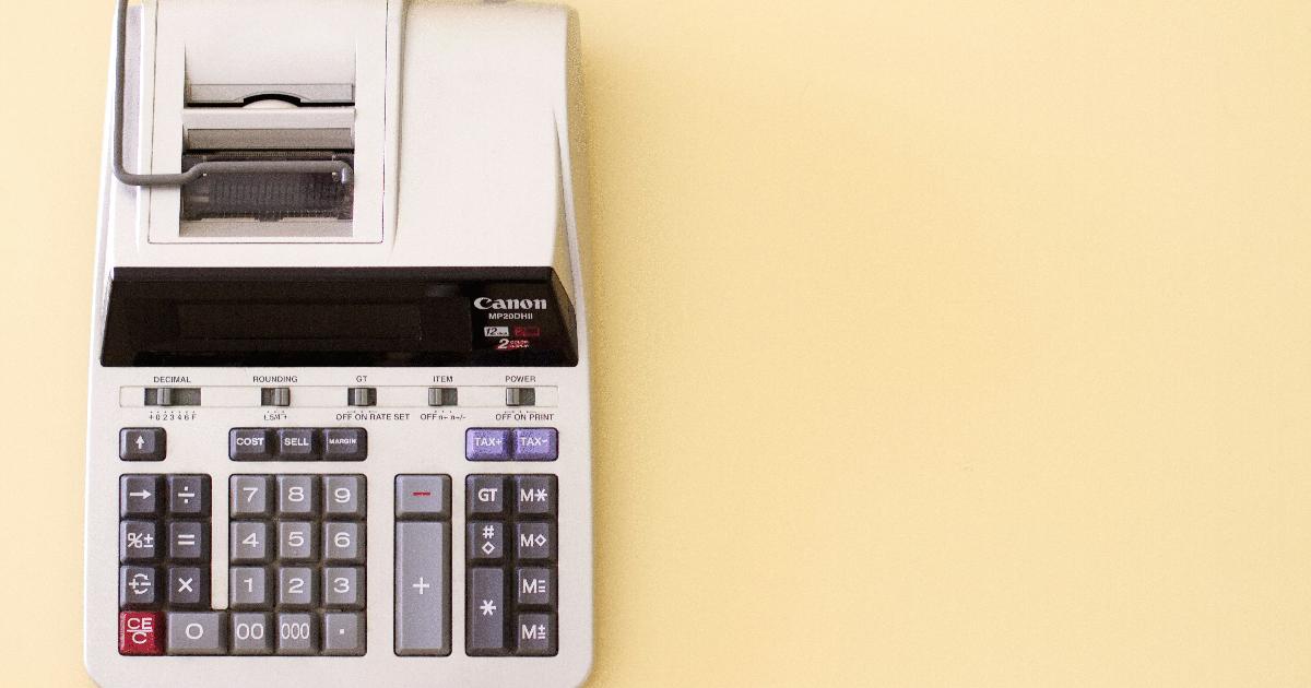 A shopping cart full of groceries beside a calculator, illustrating a flexible budget that can handle higher food costs