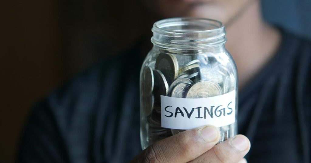 A simple household budget notebook beside a savings jar, showing quiet money habits that support a focus keyword phrase for long-term financial progress