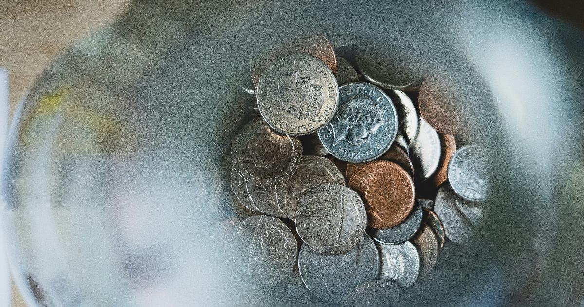 A simple savings jar next to a notebook, showing a savings challenge for building money habits