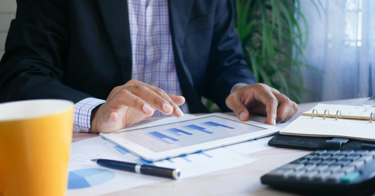 A person reviewing a money plan and retirement savings after a raise, with documents and a laptop on the desk