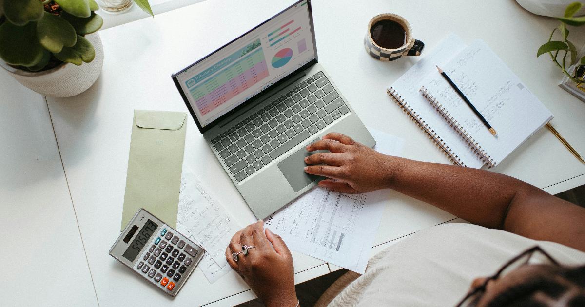 A person reviewing a financial planning worksheet with a notebook, calculator, and simple budget charts on a desk