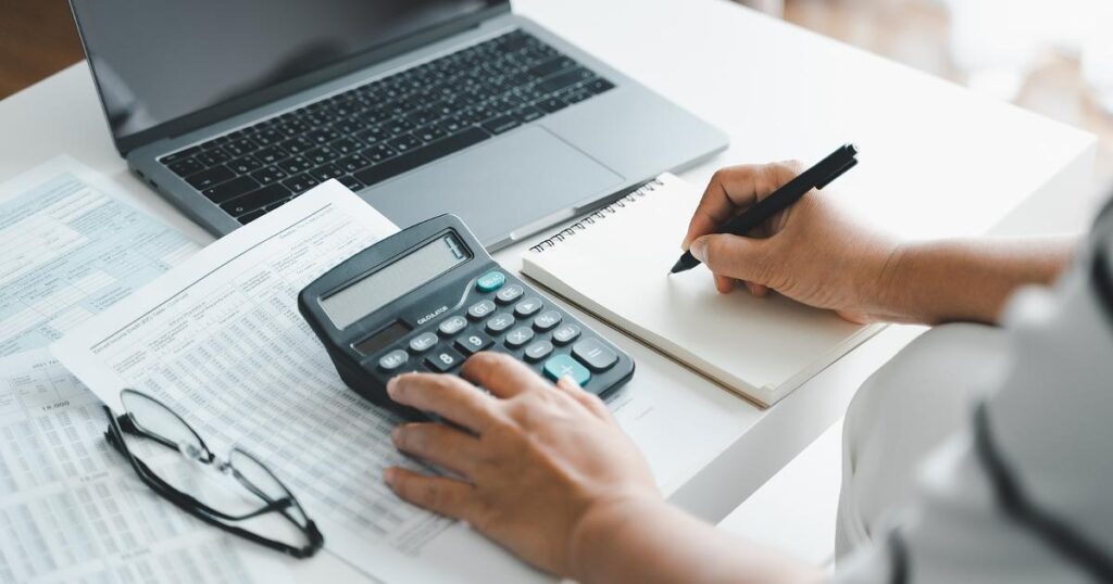 A person reviewing monthly expenses on a calculator, illustrating the rule of 25 retirement number