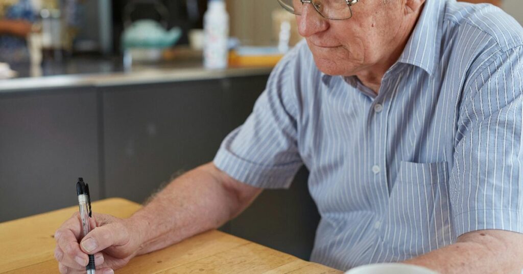 A senior reviewing retirement paperwork and a budget notebook, illustrating a solo retirement plan for one household