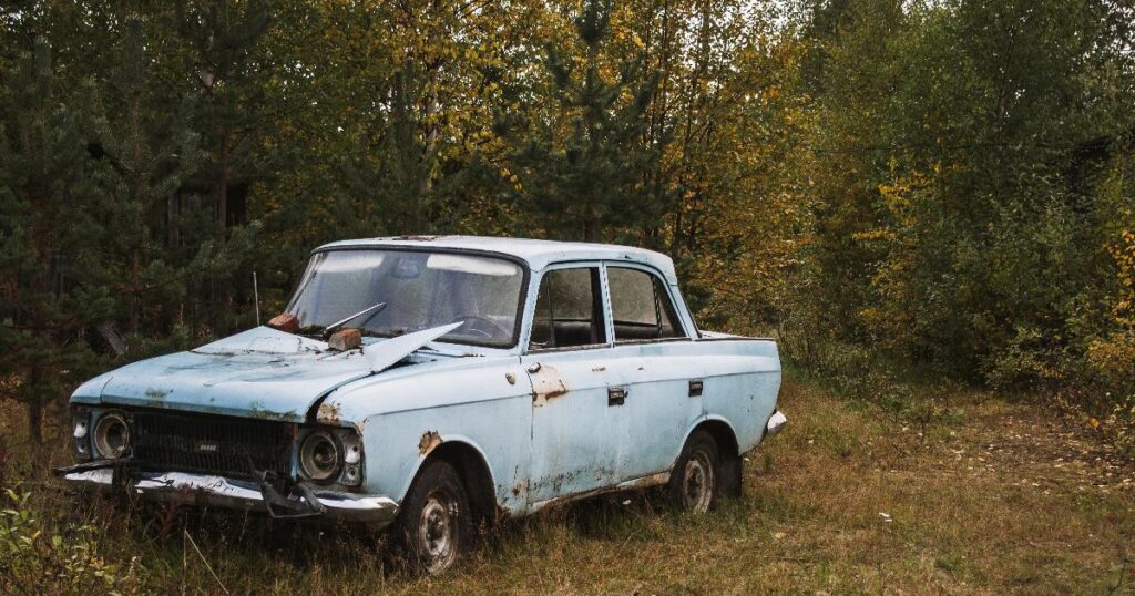 A rusty first car parked in a driveway, showing how total cost of ownership can matter more than the sticker price