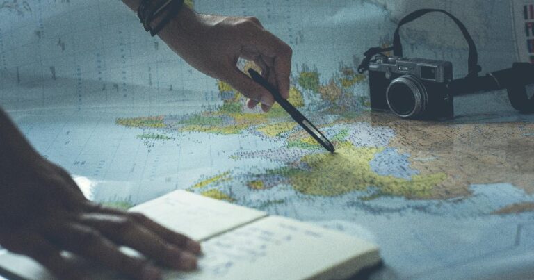 A travel budget framework on a notebook beside a map, calculator, and passport for planning a trip within budget