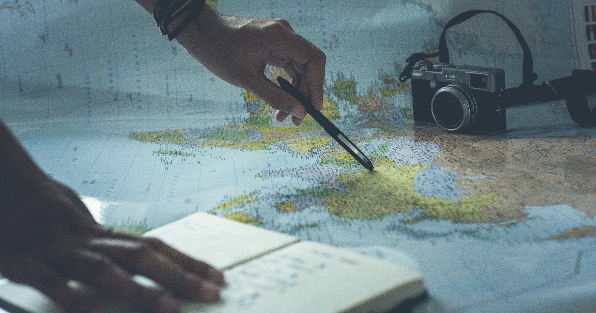 A travel budget framework on a notebook beside a map, calculator, and passport for planning a trip within budget