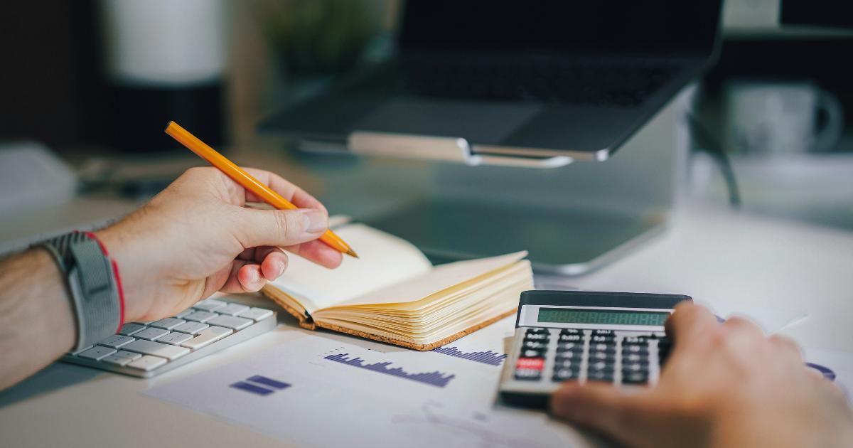 A person reviewing savings accounts and ISA rules on a laptop, with notes and calculator on the table