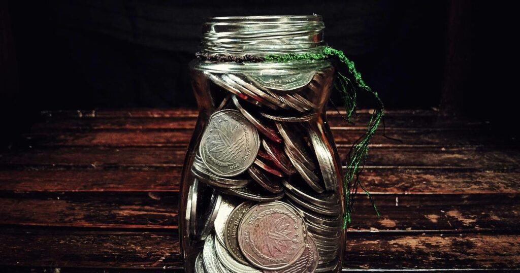 A jar filled with one-dollar bills beside a notebook tracking a $1 savings challenge