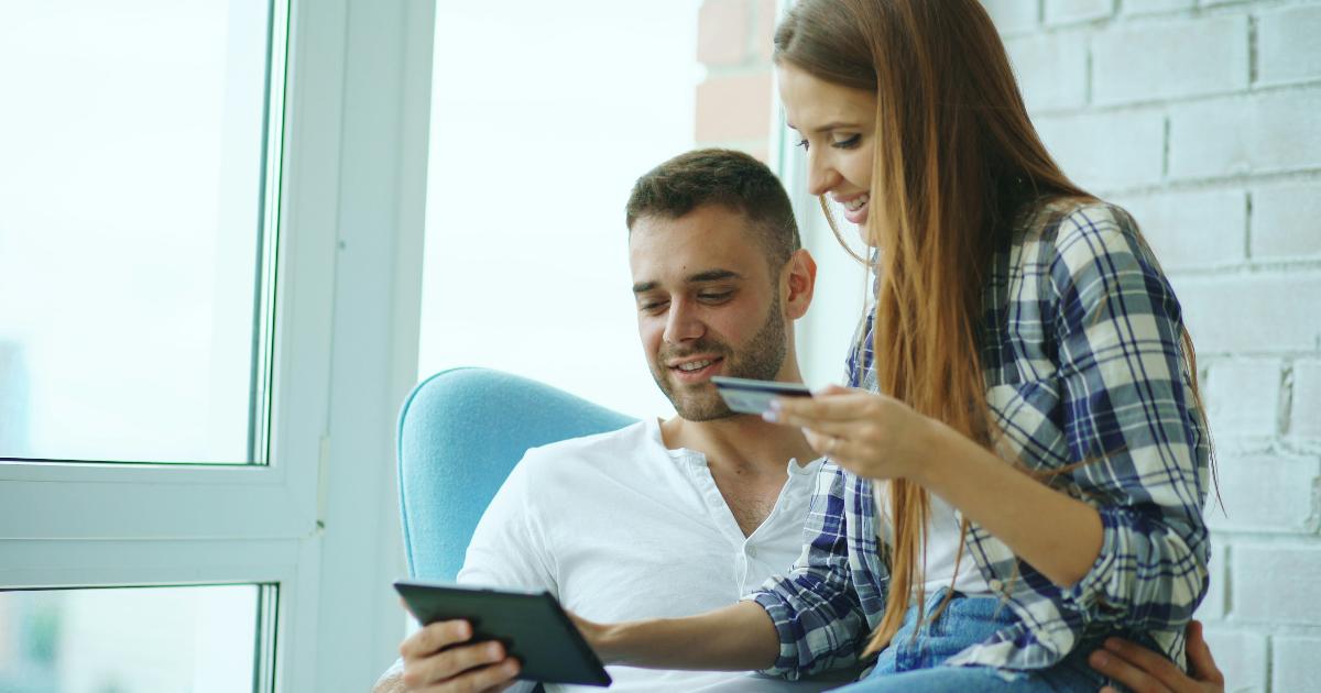 A couple reviewing a shared budget dashboard together on a laptop at the kitchen table