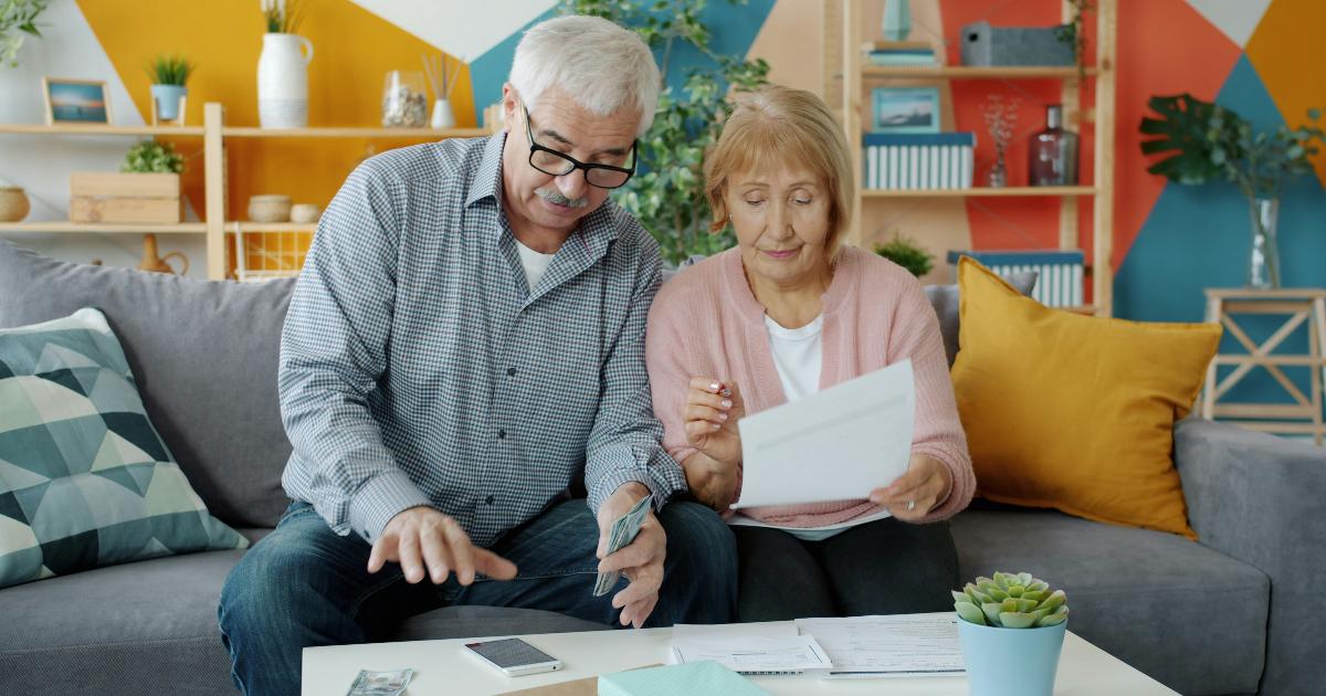 A worried family reviewing bills and bank statements at a kitchen table, showing the need to protect money first when addiction affects a home